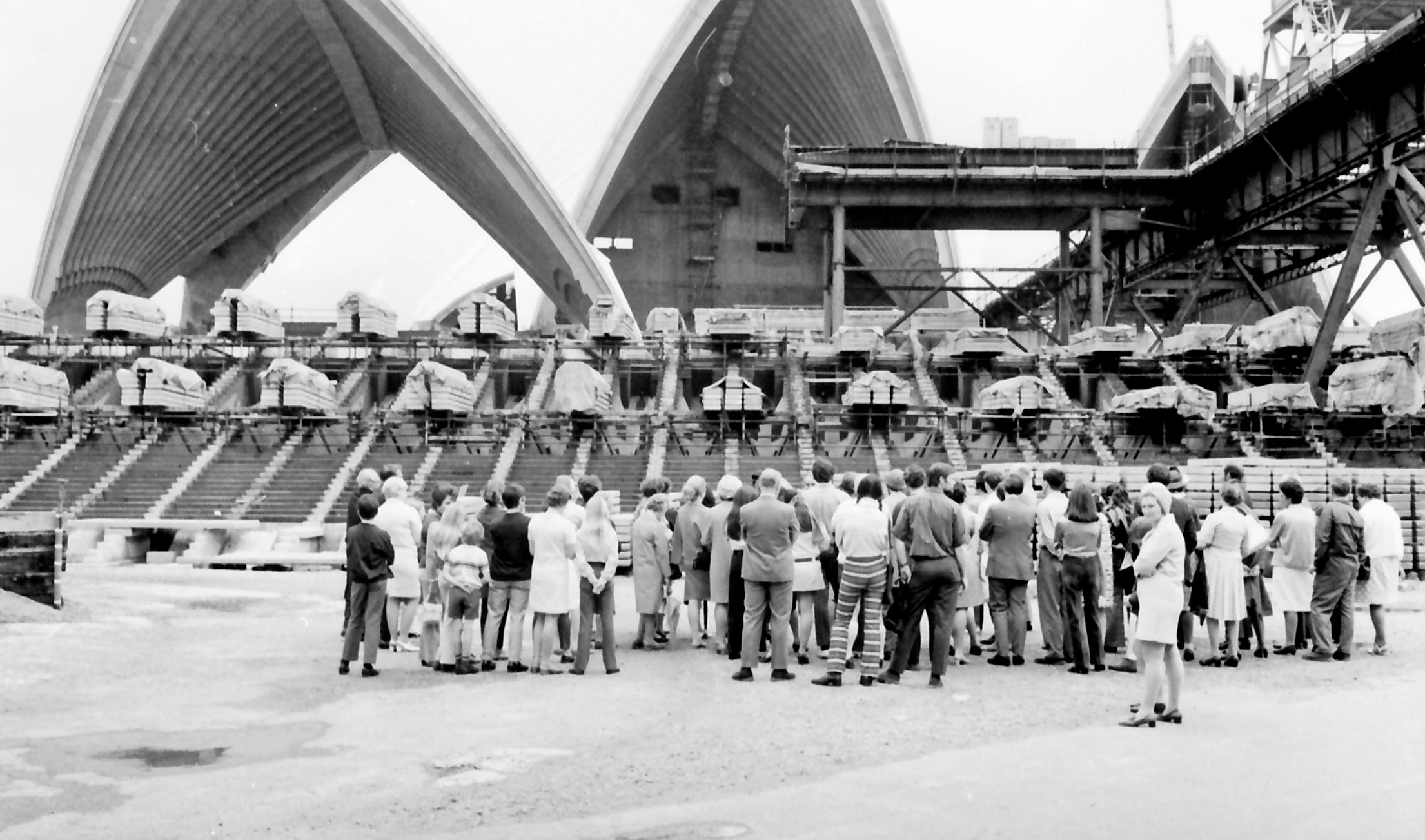 People on Circular Quay watching the construction of the Opera House shells.